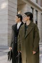 Two stylish women in elegant coats standing outdoors with briefcases, showcasing urban fashion.